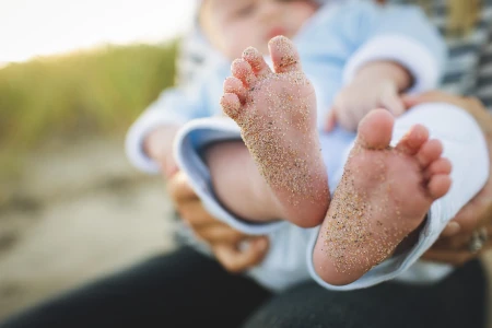 bebe com os pes cheios de areia