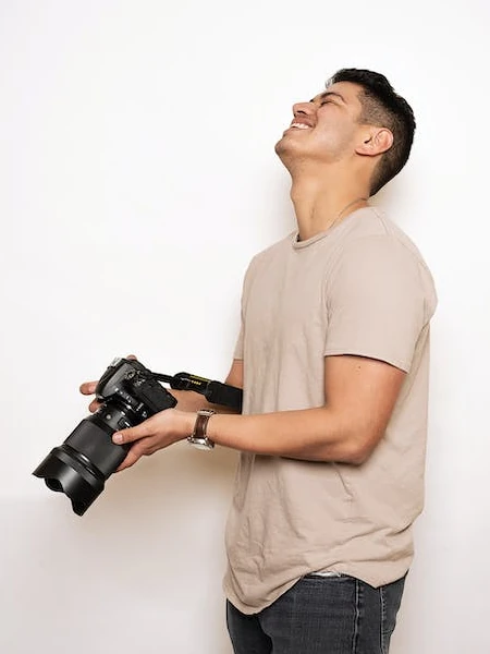 jovem sorrindo com uma DSLR nas mãos