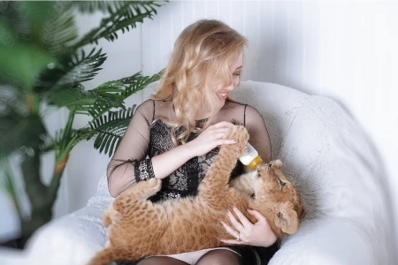 mulher dando mamadeira para um pequeno leão