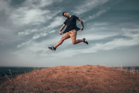 jovem saltando monte em ângulo baixo