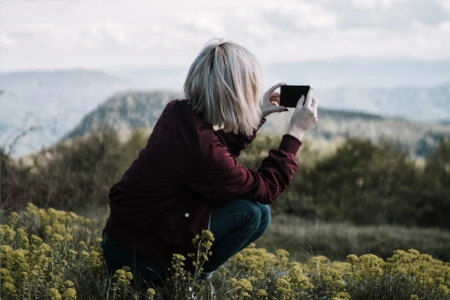 Jovem fotografando lindas paisagens com um celular.