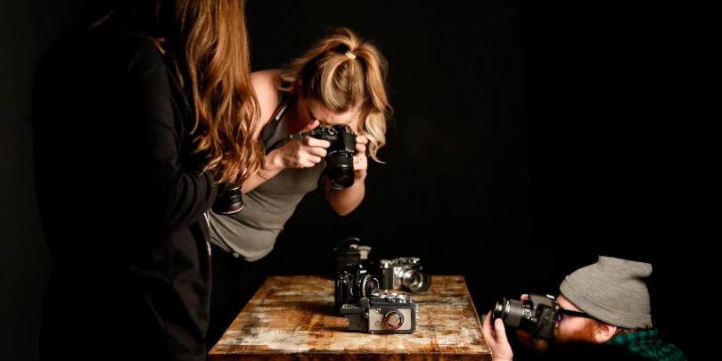 Fotógrafos ao redor de uma mesa fotografando câmeras DSLR para fotógrafos profissionais