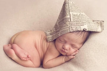 Bebê dormindo em pose fotográfica.