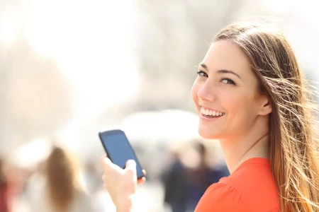 mulher sorrindo com celular nas mãos