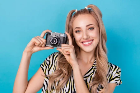 Modelo sorrindo com câmera na mão