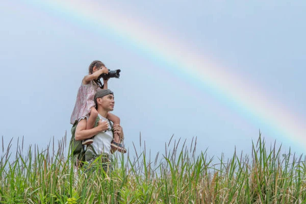 Pai e filha fotografando arco-íris