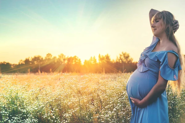 Mulher grávida em pose ao nascer do sol.